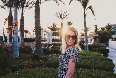 Portrait of smiling young woman standing by plants