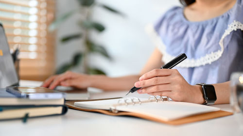 Midsection of woman using laptop on table