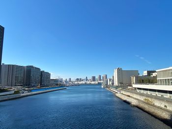 River amidst buildings against clear blue sky