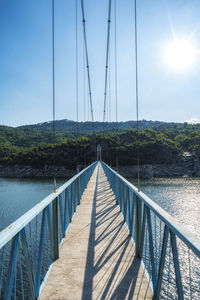 Footbridge over river against sky