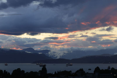 Scenic view of lake against dramatic sky during sunset