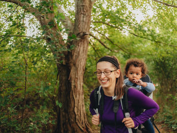 Mother carrying son on back waking on forest