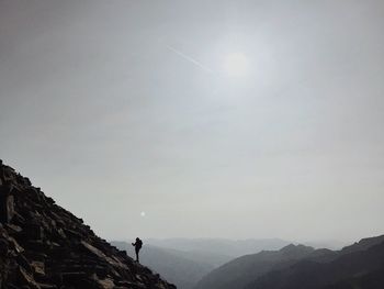 Low angle view of man standing on mountain against sky