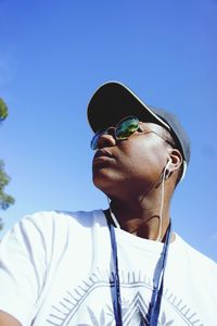 Portrait of young man wearing sunglasses against clear blue sky