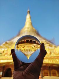 Midsection of person holding crystal ball against pagoda