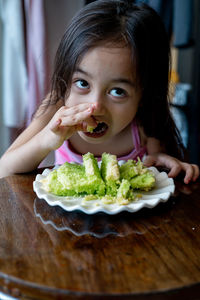 Portrait of girl with ice cream on table