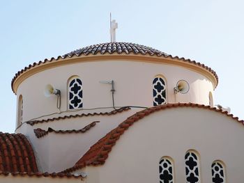 Low angle view of cross against building against clear sky