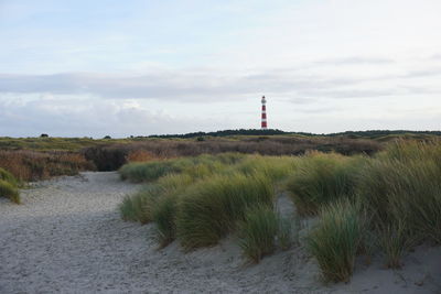 Lighthouse by sea against sky