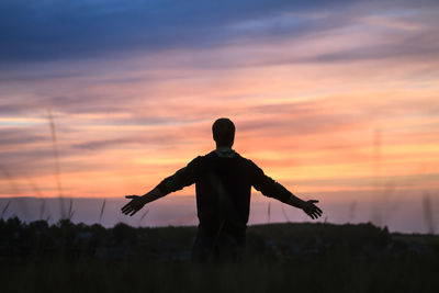 Silhouette man on field against sky during sunset