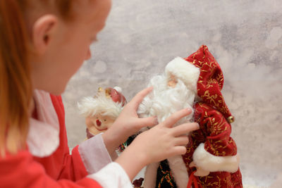 Close-up of girl holding santa claus figurine at home