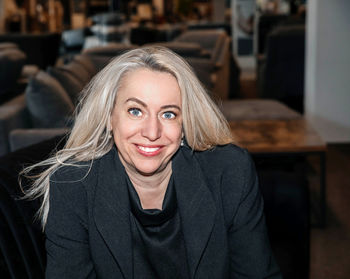 Confident professional woman with platinum blonde hair in a chic black blazer smiling 