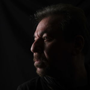 Portrait of man looking away against black background