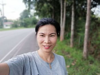 Portrait of woman on road against trees