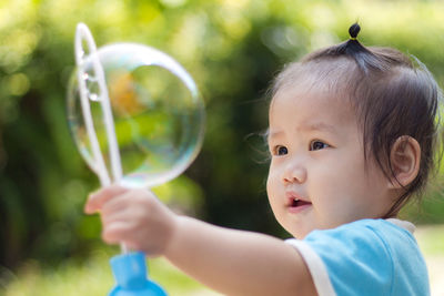 Close-up of cute girl making bubble with wand