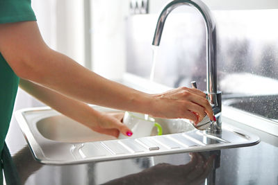 Midsection of woman with reflection in water at home