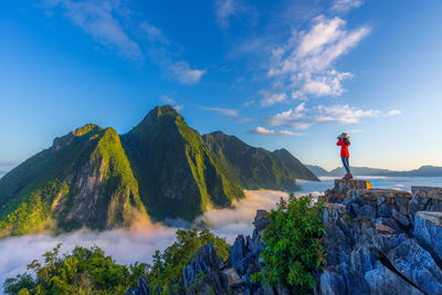 Rear view of man standing on mountain against sky