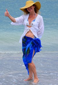 Happy woman showing thumbs up sign at beach