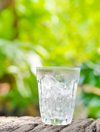 Close-up of ice cube in drinking glass on retaining wall