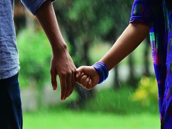 Close-up of couple holding hand in rain