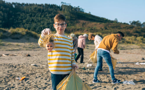 Boy showing broken doll while cleaning beach