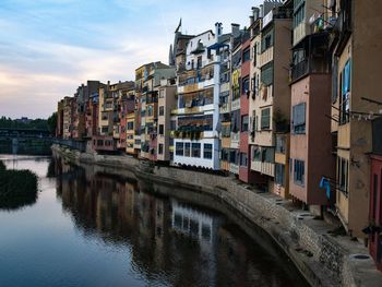 Buildings by river in town against sky