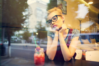 Young woman looking away while sitting by table at cafe