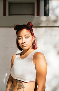 Portrait of beautiful young woman standing against wall