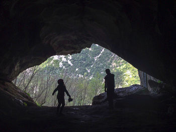 Silhouette people standing in cave