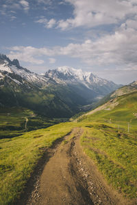 Scenic view of road amidst field against sky