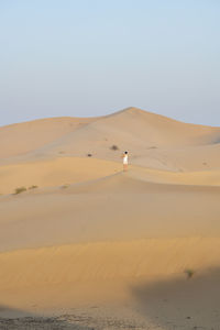 Woman taking a pictures of dunes in the desert at sunset