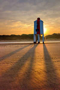 Lifeguard hut at beach against sky during sunset