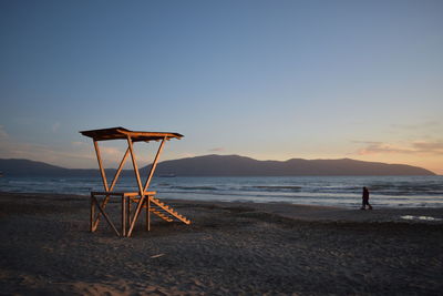 Lifeguard hut on beach against sky during sunset