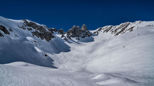 Scenic view of snowcapped mountains against clear blue sky