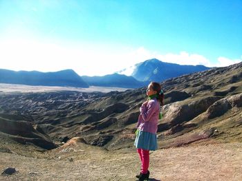 Rear view of man standing on mountain against sky