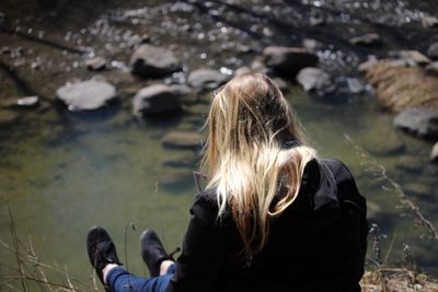 High angle view of woman sitting against pond