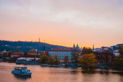 River by buildings against sky during sunset