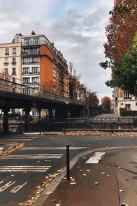 Road by buildings in city against sky