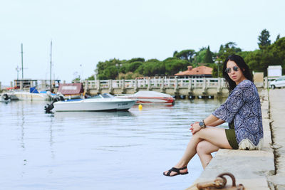 Portrait of smiling young woman sitting on boat against clear sky