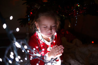 Portrait of girl looking at illuminated christmas tree