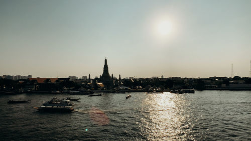 View of buildings by river against clear sky