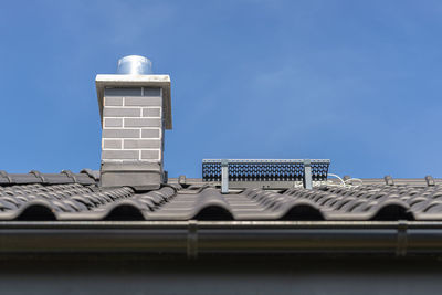 The roof of a single-family house covered with a new ceramic tile in anthracite, system chimneny.