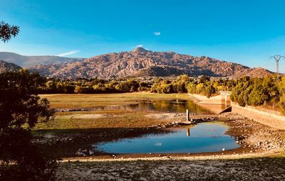 Scenic view of lake and mountains against blue sky