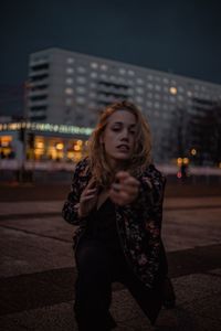 Young woman looking away while standing in city at night