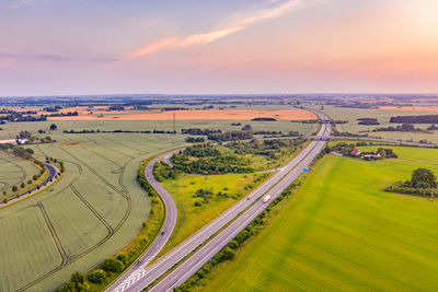 High angle view of road amidst field against sky during sunset