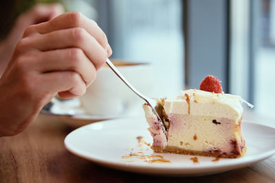 Woman have breakfast at cafe, eating raspberry cheesecake with coffee