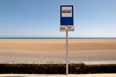 Information sign against beach and sky on sunny day