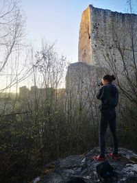 Full length of woman standing on rock against sky