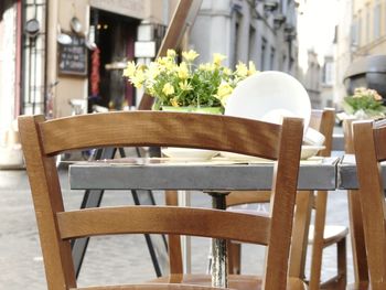 Empty chairs and tables at sidewalk cafe against building
