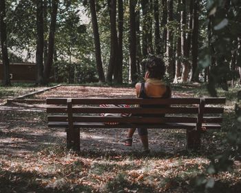 Rear view of man sitting on bench in park
