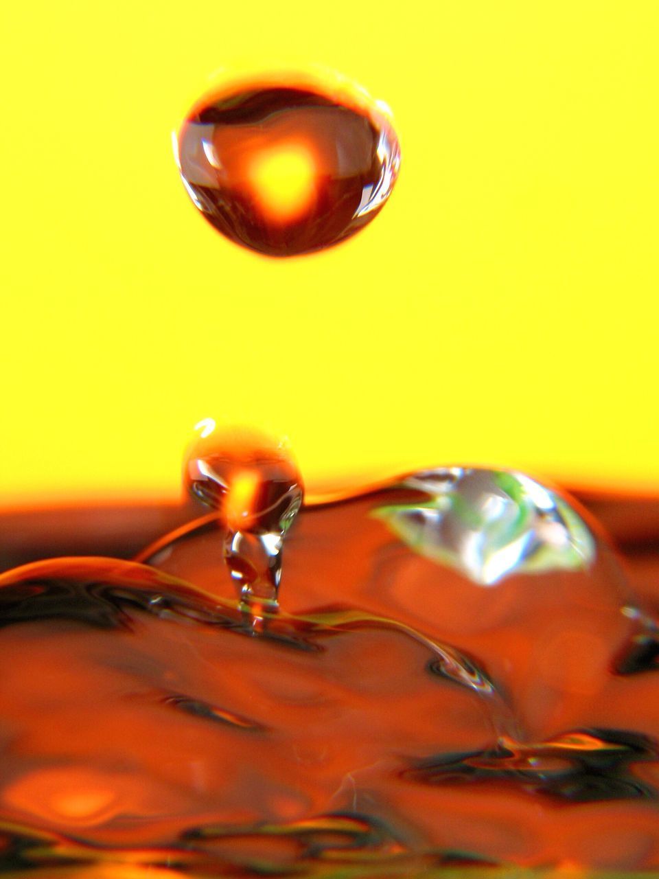 CLOSE-UP OF DROP FALLING ON WATER IN ORANGE